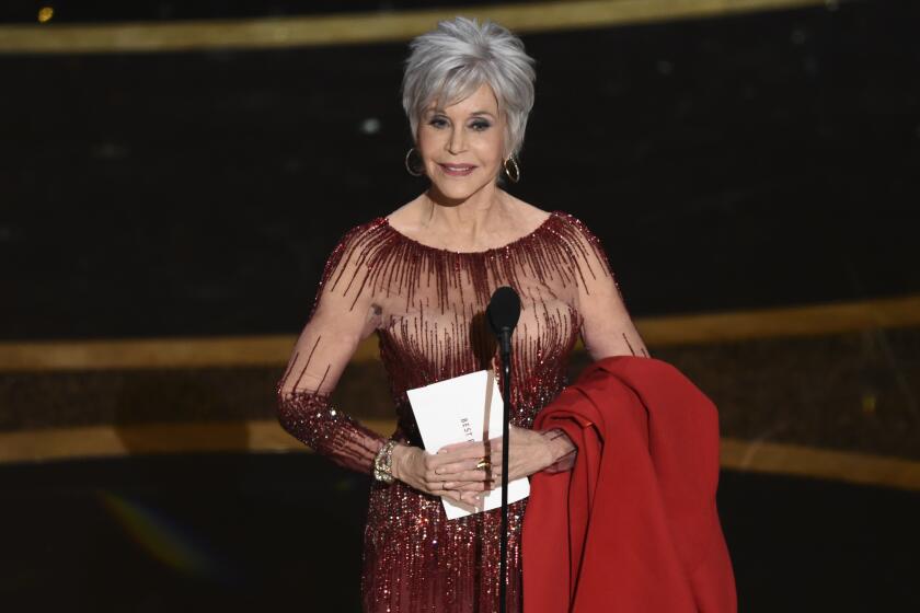 Jane Fonda holding an Oscars envelope on stage