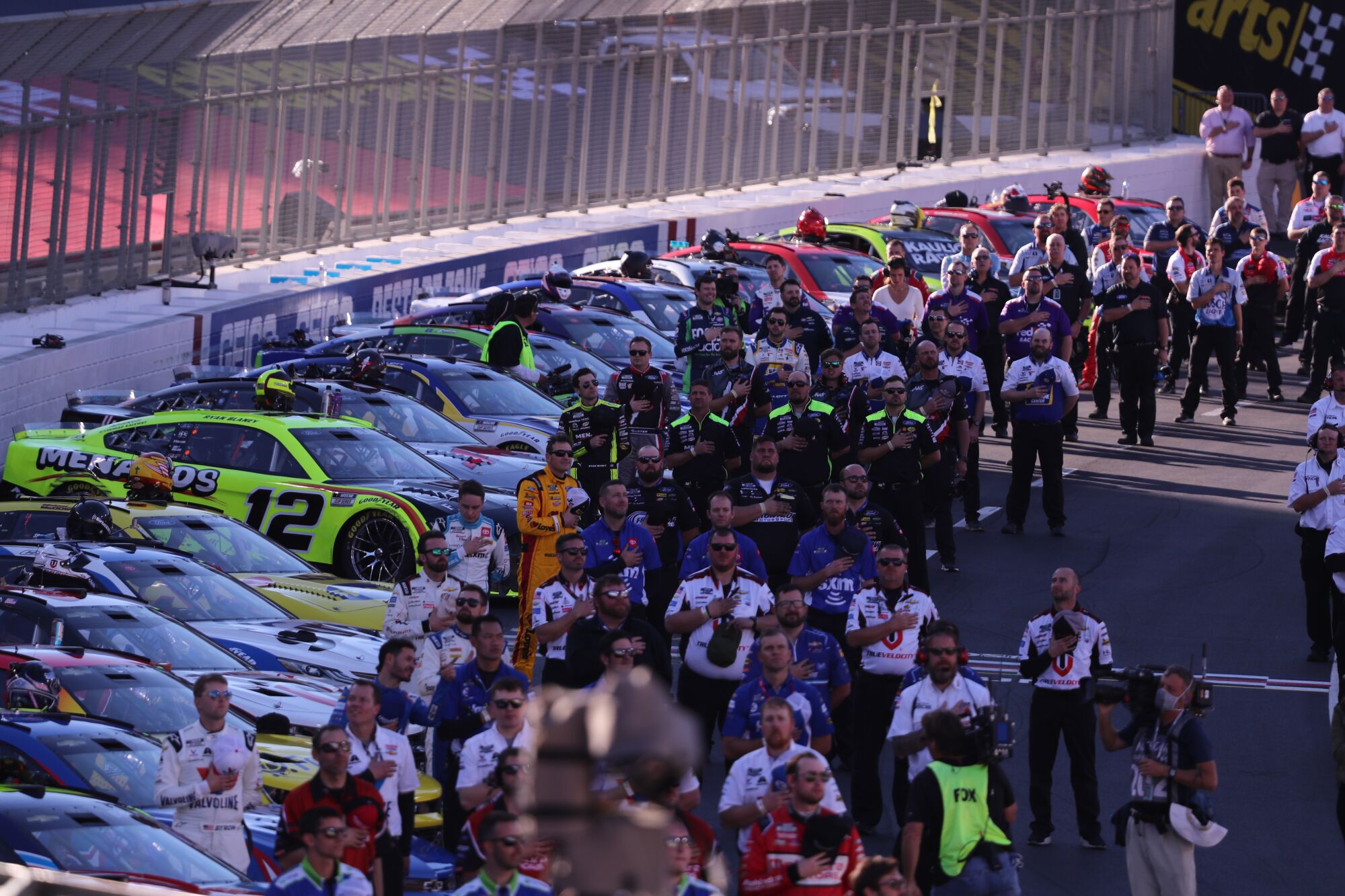 NASCAR racers and crew line the track while the national anthem is played at the Busch Light Clash.