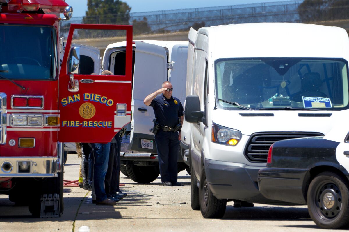 An SDPD officer salutes as a body is loaded into the coroner's van on Interstate 5.
