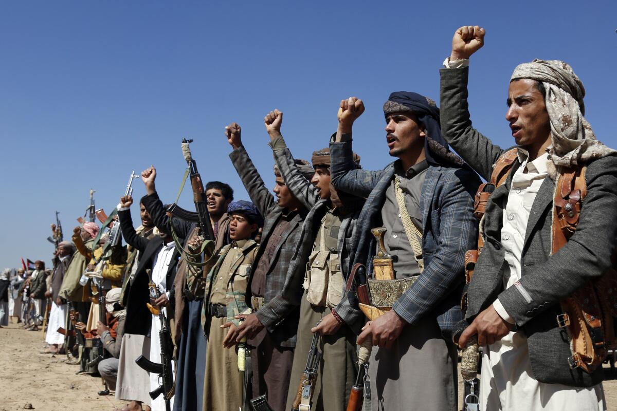 Houthi fighters and tribesmen raise their fists in protest