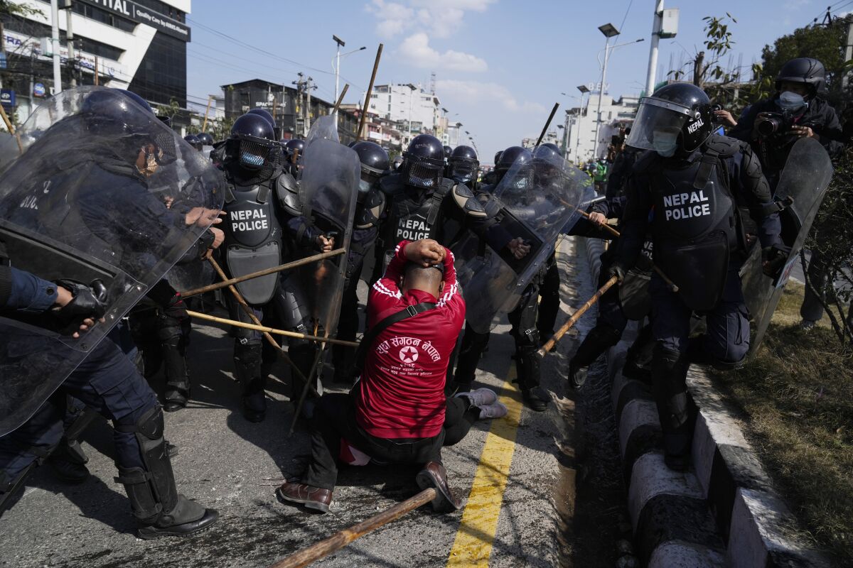 Nepalese police with batons charge at a protester.