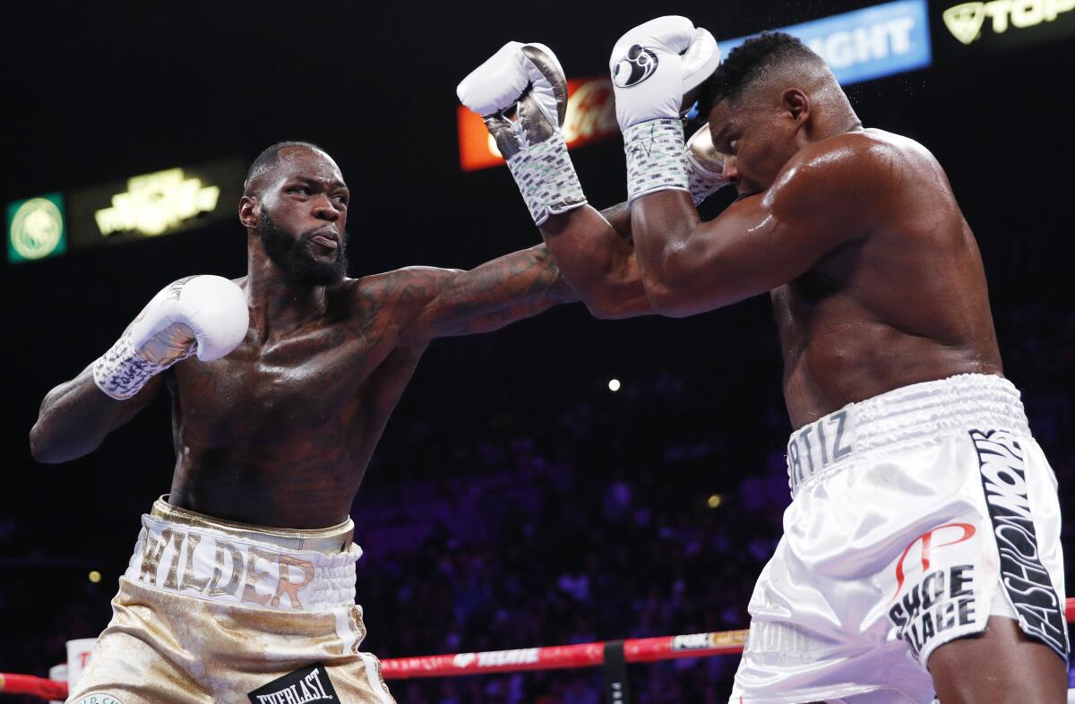Deontay Wilder, left, throws a left at Luis Ortiz during the WBC heavyweight title boxing match on Saturday in Las Vegas.