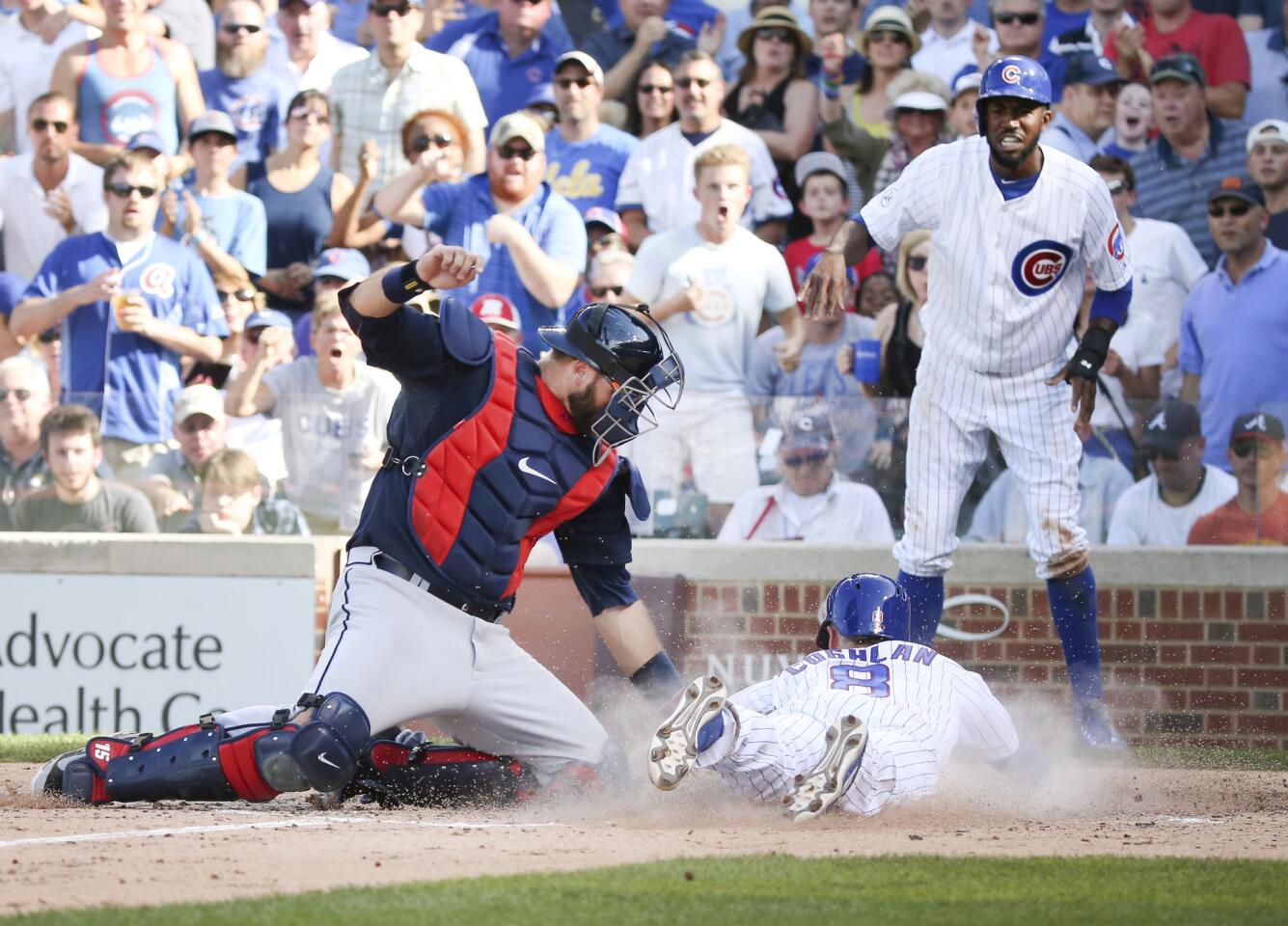 Cubs left fielder Chris Coghlan scores in front of Atlanta Braves catcher A.J. Pierzynski on the double by third baseman Kris Bryant during the fifth inning.