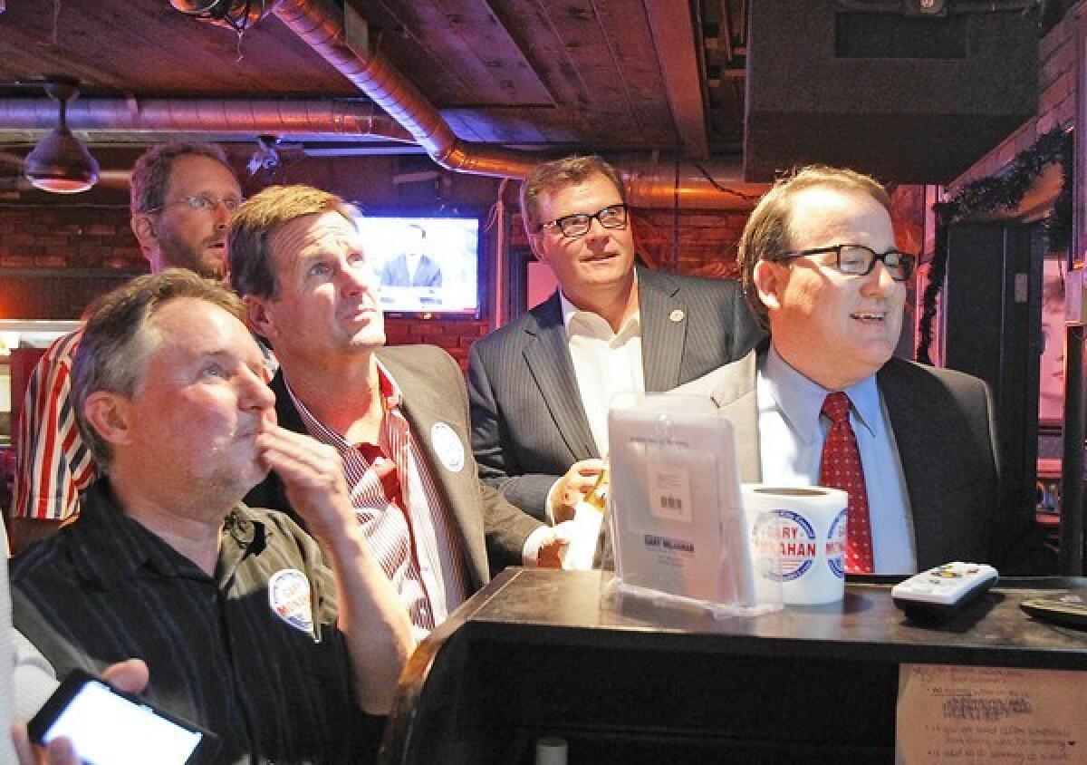 Gary Monahan, far left; Steve Mensinger, second from right and then-Mayor Pro Tem Jim Righeimer, at right, gathered in 2012 to watch early returns in the council race. The three men are among six former Costa Mesa mayors calling for city leaders to reopen parts of the economy, including lifting restrictions on city parks, golf courses and trails.