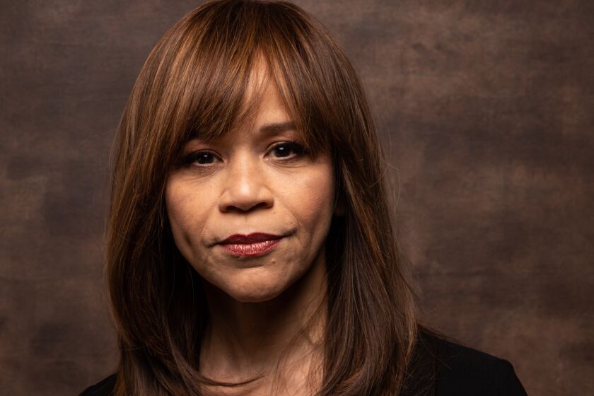 Woman, Rosie Perez, posing in black with slight smile at Sundance Film Festival with long brown hair with bangs