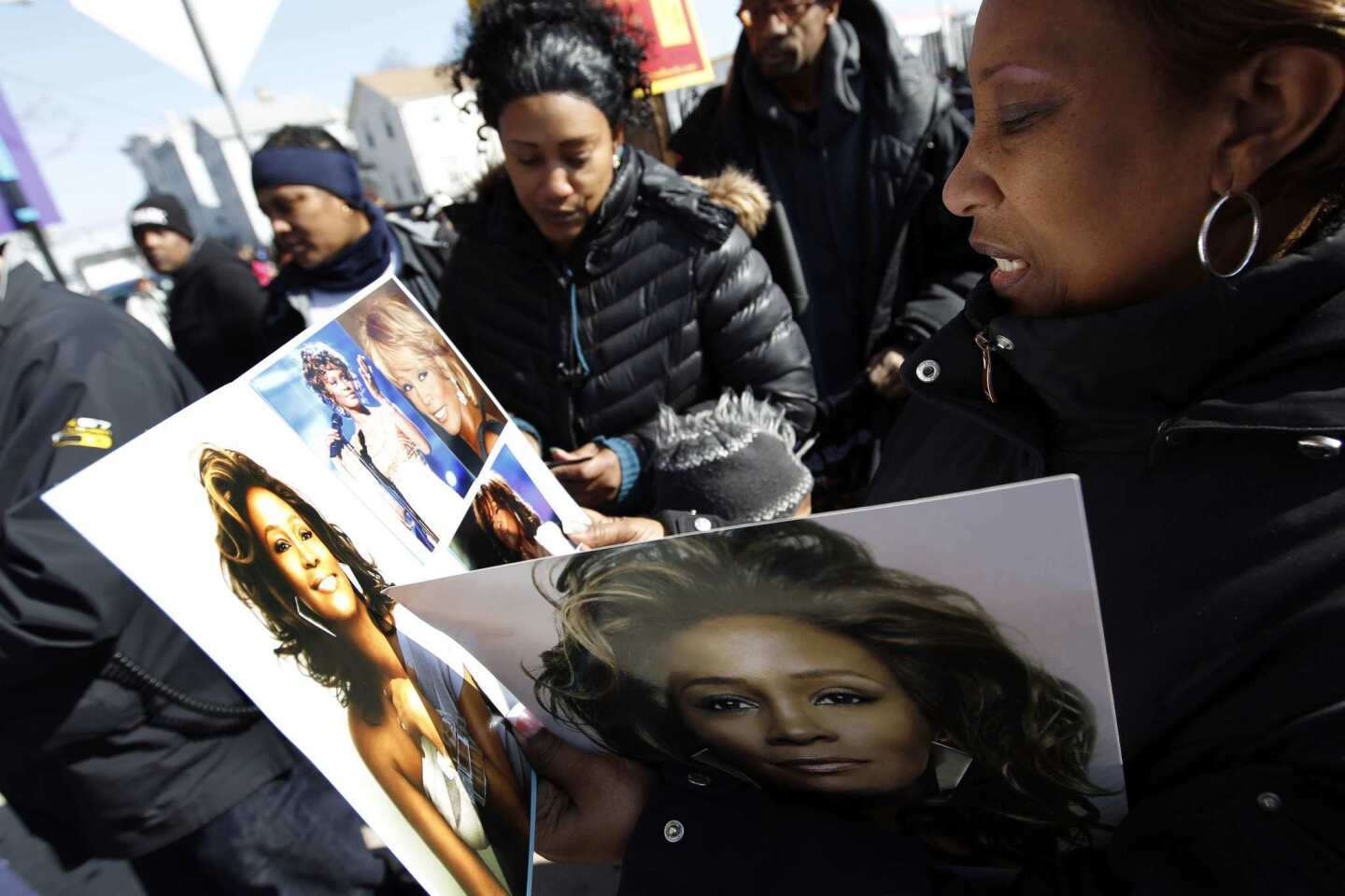 A Whitney Houston fan looks at photos of the singer a few blocks from the New Hope Baptist Church before Houston's funeral in Newark, N.J.