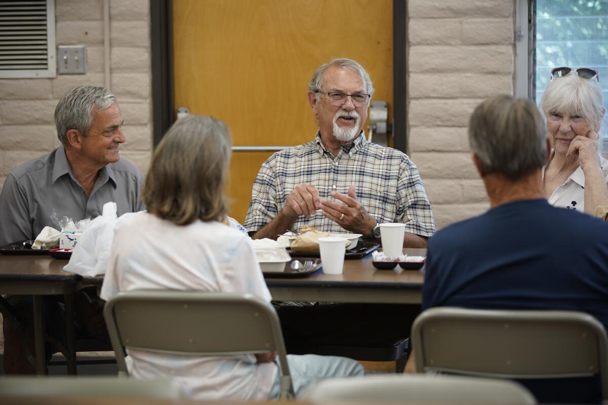 A senior man chats with his lunchmates at an Adult Enrichment Center.