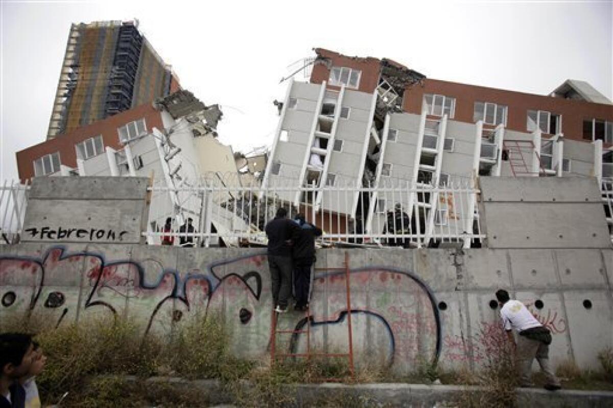 People look at a collapsed building in Concepcion, Chile, Sunday, Feb. 28, 2010. A 8.8-magnitude earthquake hit Chile early Saturday. (AP Photo/ Natacha Pisarenko)