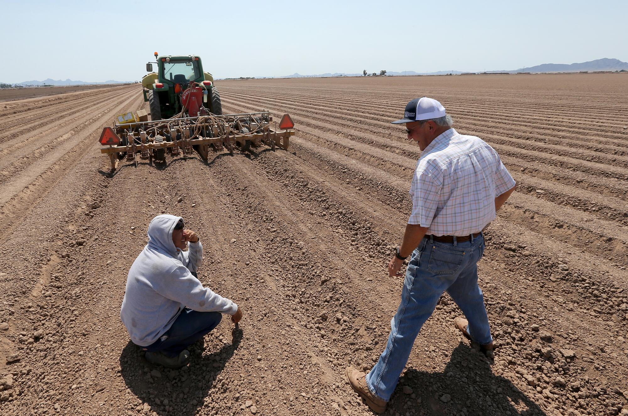 Farmer Bart Fisher shares a laugh with a worker while looking over seeding operations at one of his fields in Blythe.