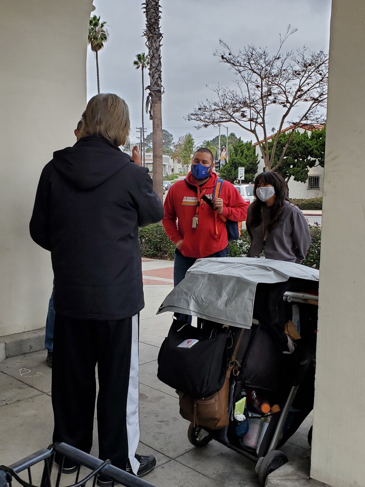 Miguel Figueroa and Jayna Lee speak to a homeless man to see what services they may be able to offer.