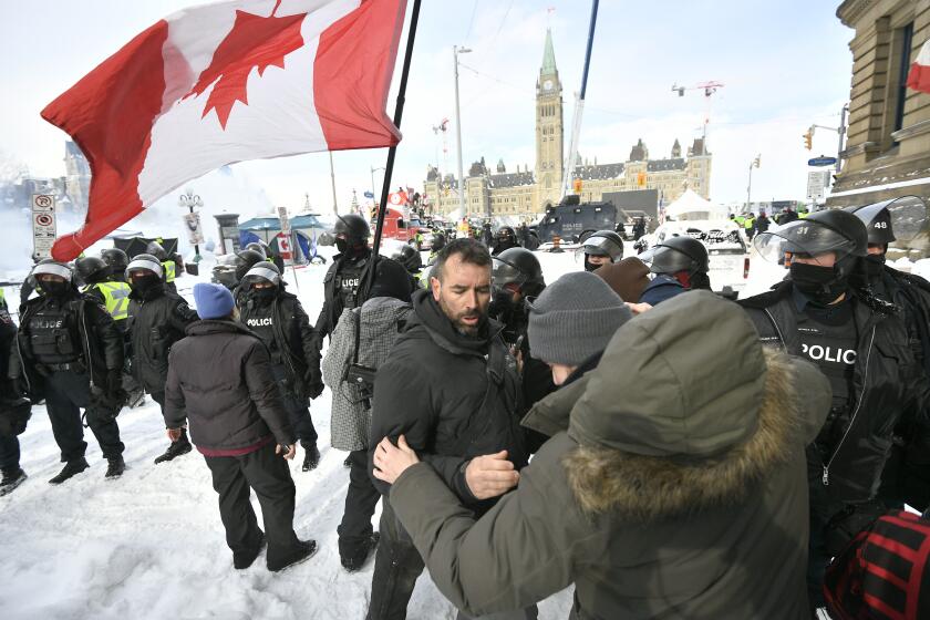 Police move in to clear downtown Ottawa near Parliament Hill on Saturday, Feb. 19, 2022. Police resumed pushing back protesters on Saturday after arresting more than 100 and towing away vehicles in Canada’s besieged capital, and scores of trucks left under the pressure, raising authorities’ hopes for an end to the three-week protest against the country’s COVID-19 restrictions. (Justin Tang /The Canadian Press via AP)