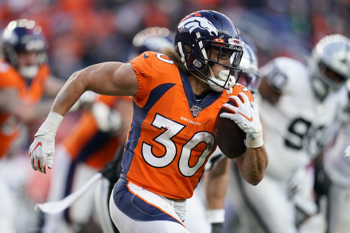 FILE - In this Dec. 29, 2019, file photo, Denver Broncos running back Phillip Lindsay runs with the ball during the second half of an NFL football game against the Oakland Raiders, in Denver. Lindsay insists his noticeably bigger biceps have nothing to do with the Broncos' signing of free agent Melvin Gordon. "I don't need another man to fuel my fire," said Lindsay, the only undrafted running back in NFL history to make it to the Pro Bowl as a rookie and to top 1,000 yards rushing in each of his first two seasons as a pro.(AP Photo/Jack Dempsey, File)