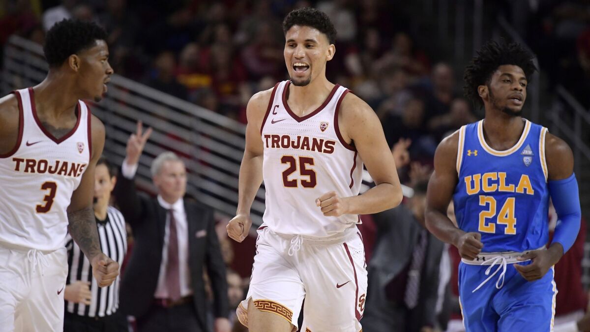 USC forward Bennie Boatwright, second from right, celebrates with guard Elijah Weaver, left, after scoring as UCLA guard Jalen Hill, right, runs behind and USC head coach Andy Enfield gestures during the second half.