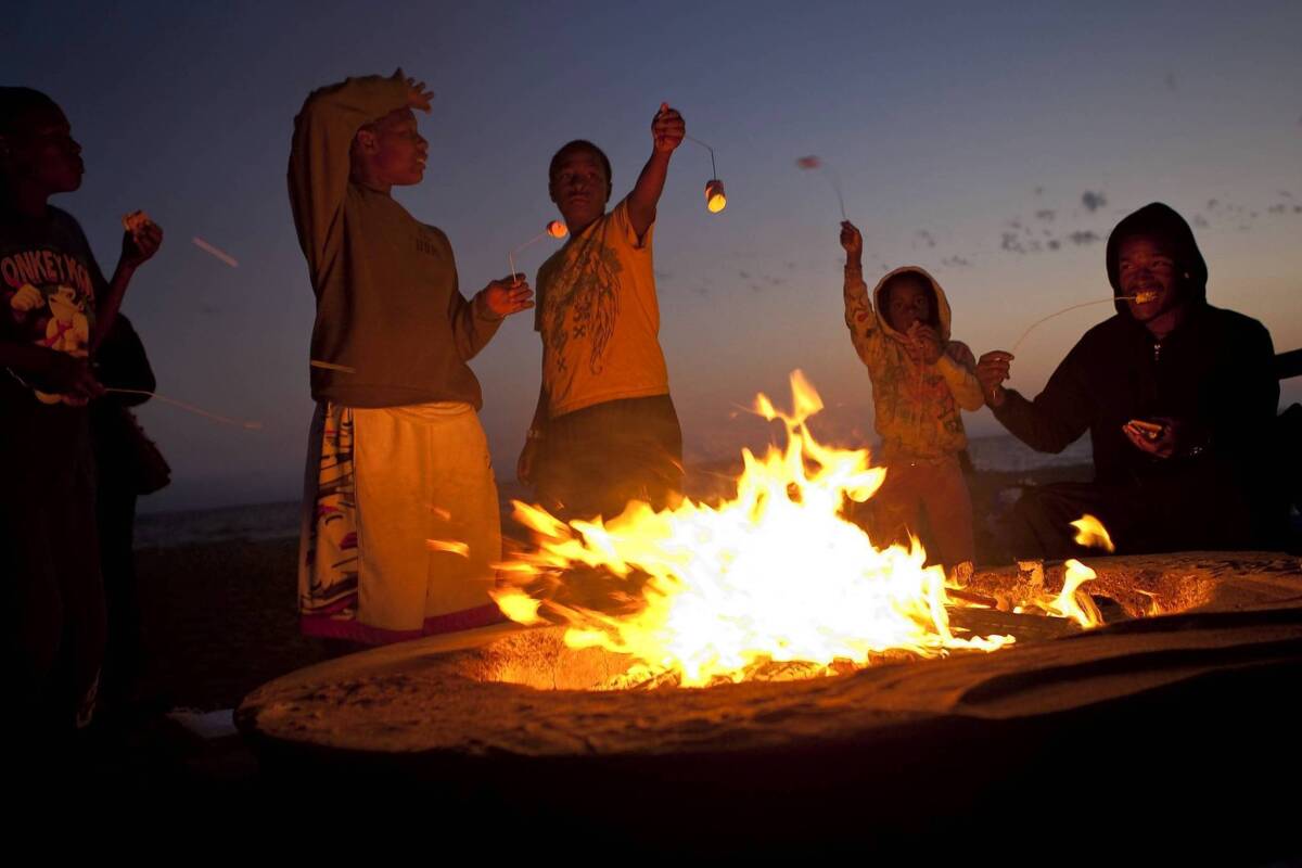 Members of the Sasser-Williams family of Los Angeles roast marshmallows at a fire pit at Dockweiler State Beach. Citing health concerns, air quality officials have proposed a year-round ban on open burning on all L.A. and Orange County beaches.