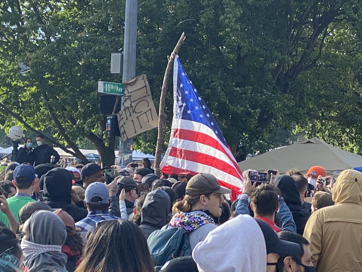 Activists in Seattle's "cop free" zone converge Saturday on an American flag held by a counter-protester.