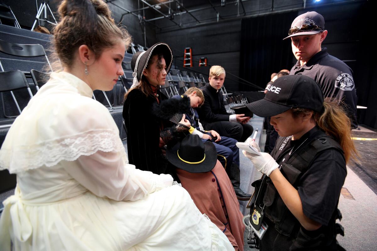 Thurston Middle School forensics student Daniela Suh interviews witnesses while investigating a mock homicide scene based on the assassination of former President Abraham Lincoln at the school in Laguna Beach on Thursday. Teachers and Laguna Beach police officers helped students investigate the crime.