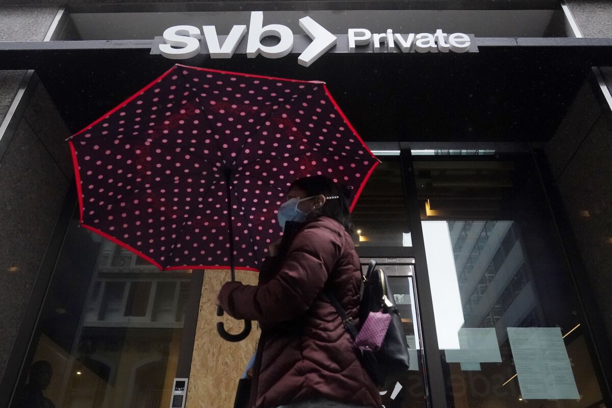 A pedestrian carries an umbrella while walking past a Silicon Valley Bank.