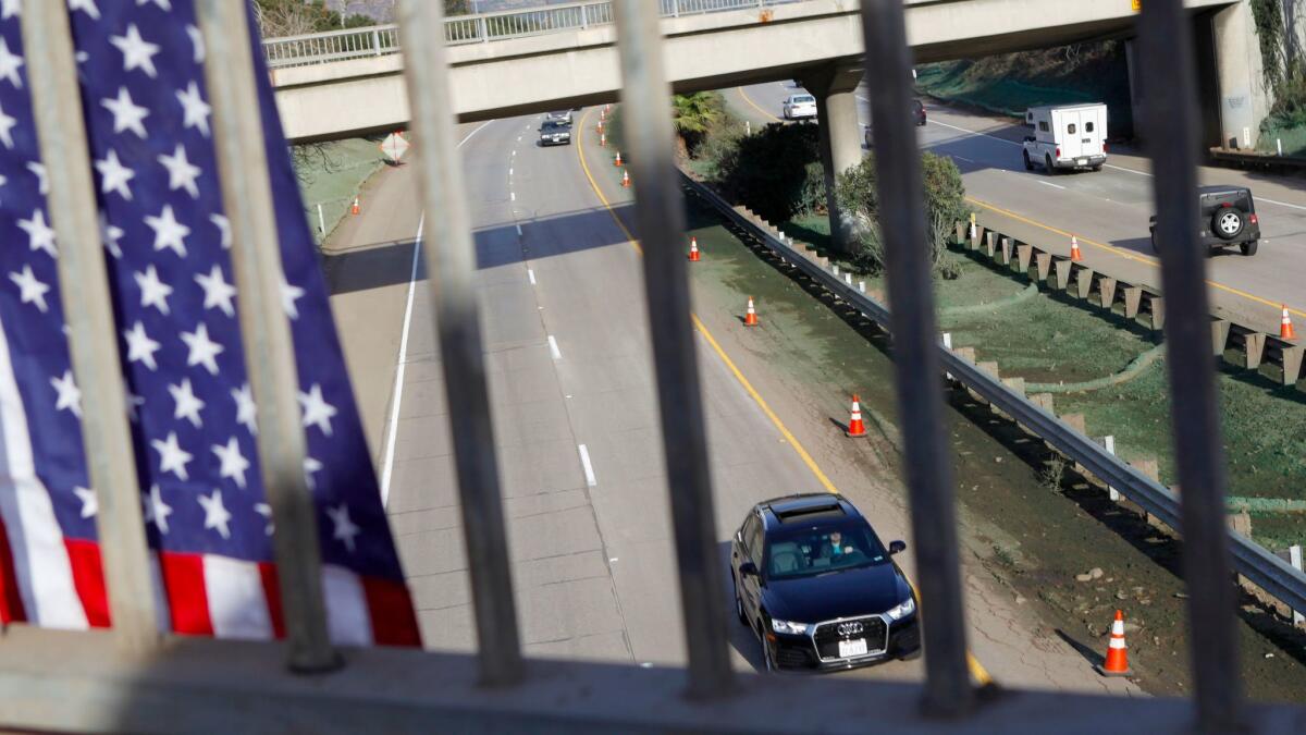 An American flag hangs from Olive Mill Road as cars travel along the reopened Highway 101 in Montecito,