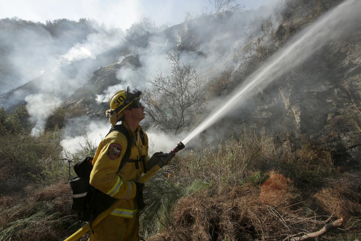 A firefighter shoots water at smoldering brush in January during one of more than 1,200 wildfires so far this year. Gov. Jerry Brown said the drought has set the stage for a dangerous and expensive fire season.