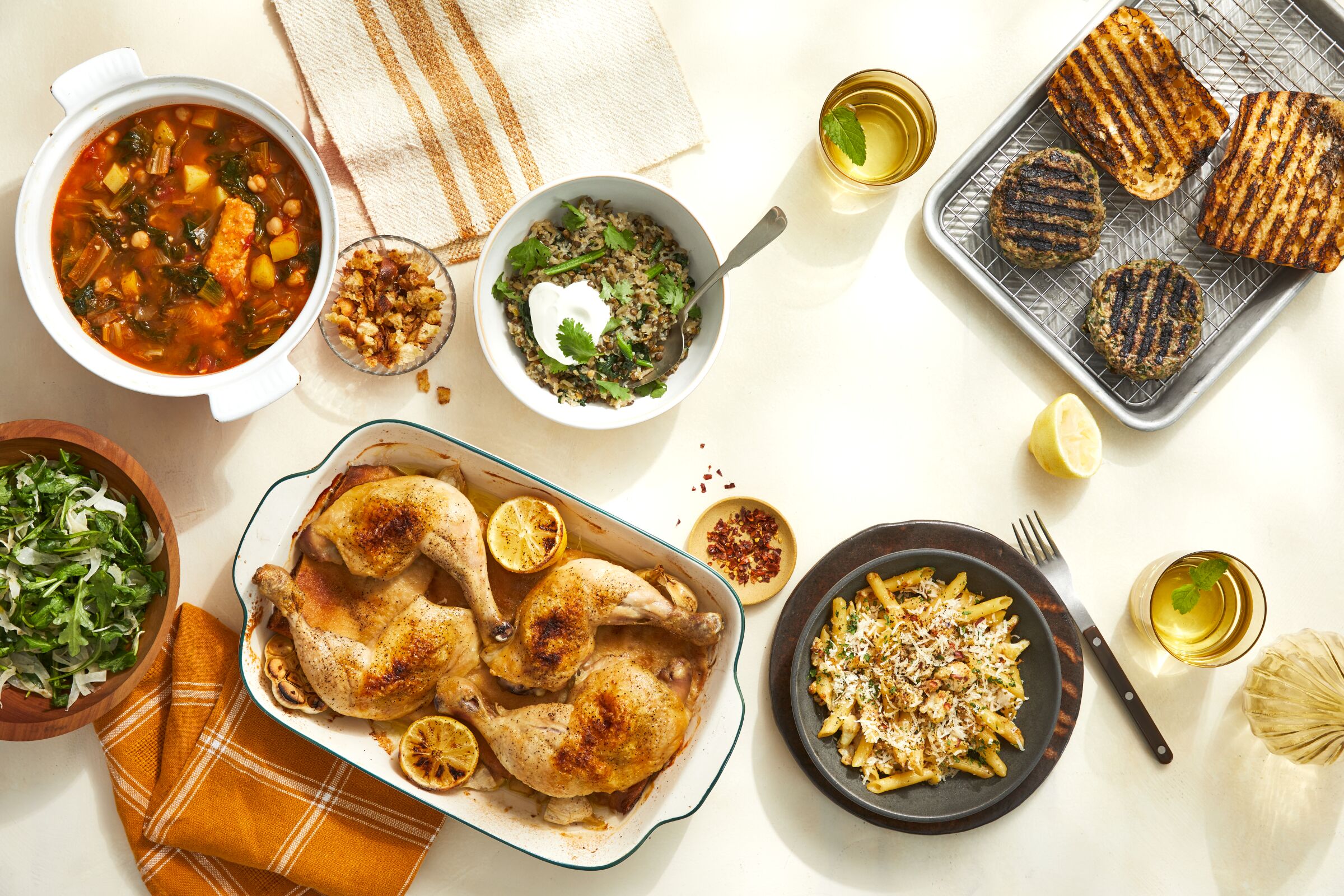Chicken legs, penne with cauliflower and other dishes on a table