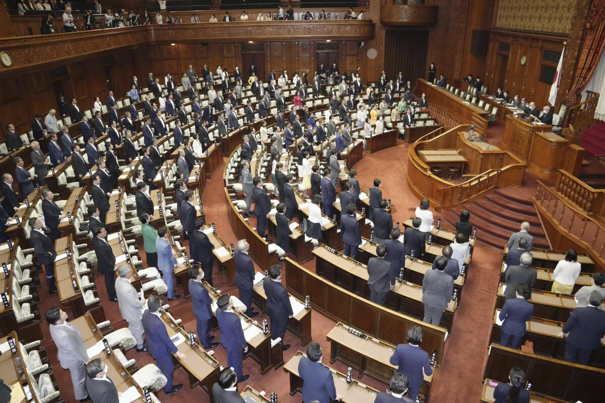 Japanese lawmakers stand in Parliament in Tokyo. 
