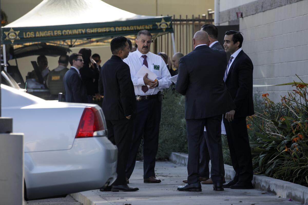 Investigators speak next to a car