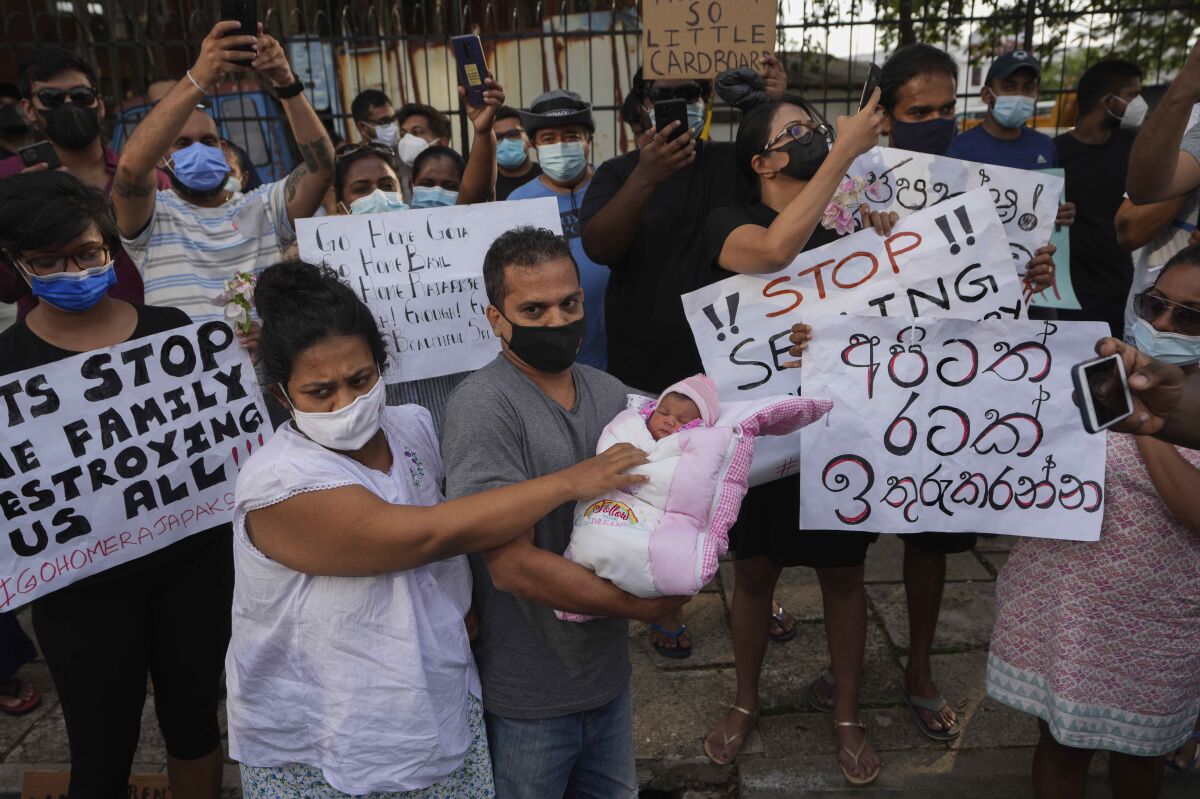 A Sri Lankan couple with their infant join an anti government protest during a curfew in Colombo, Sri Lanka, Sunday, April 3, 2022. Opposition lawmakers and people angered by the government's handling of Sri Lanka's worst economic crisis on Sunday marched to denounce the president's move to impose a nationwide curfew and state of emergency, as protests over food and fuel shortages swelled. (AP Photo/Eranga Jayawardena)