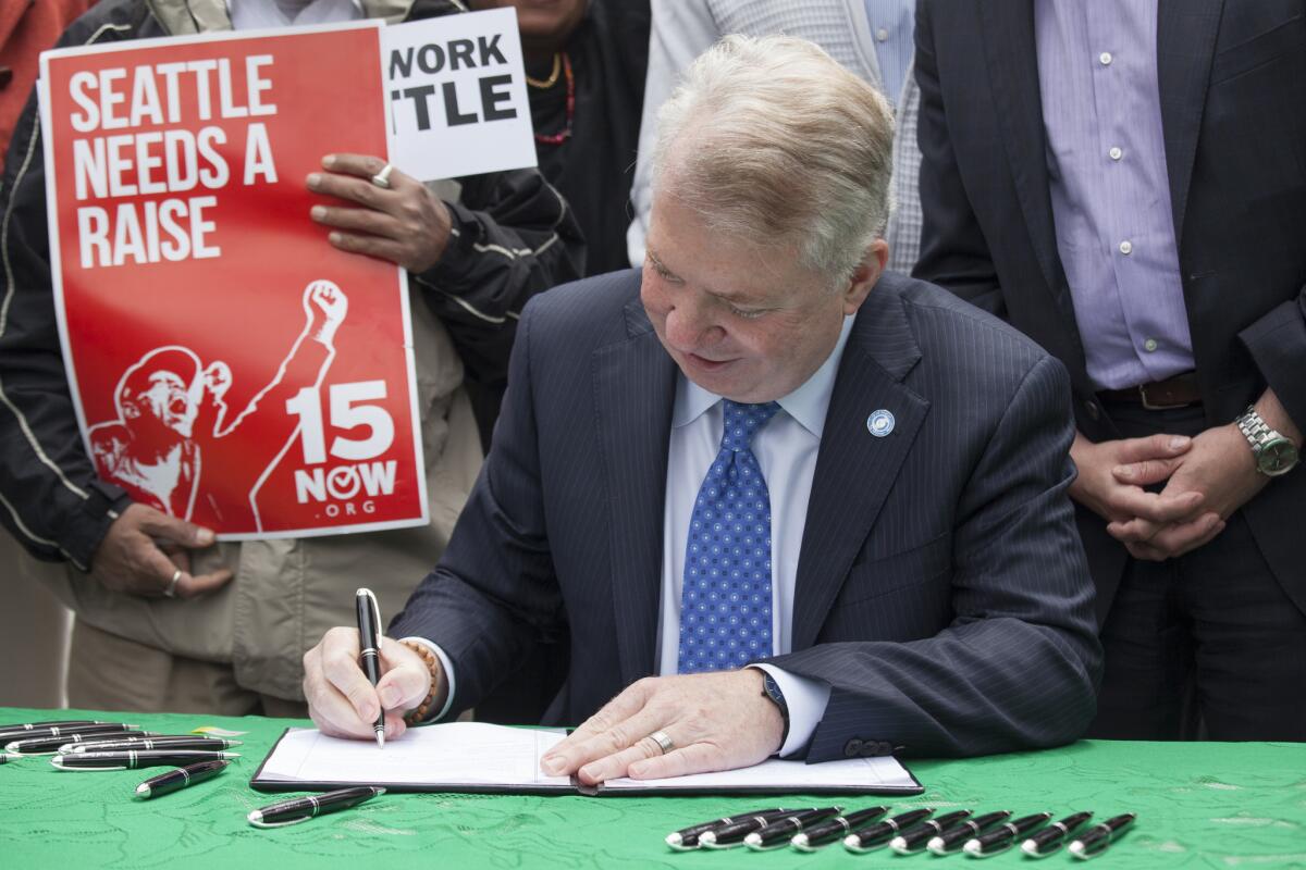Seattle Mayor Ed Murray signs a bill raising the city's minimum wage to $15 an hour.
