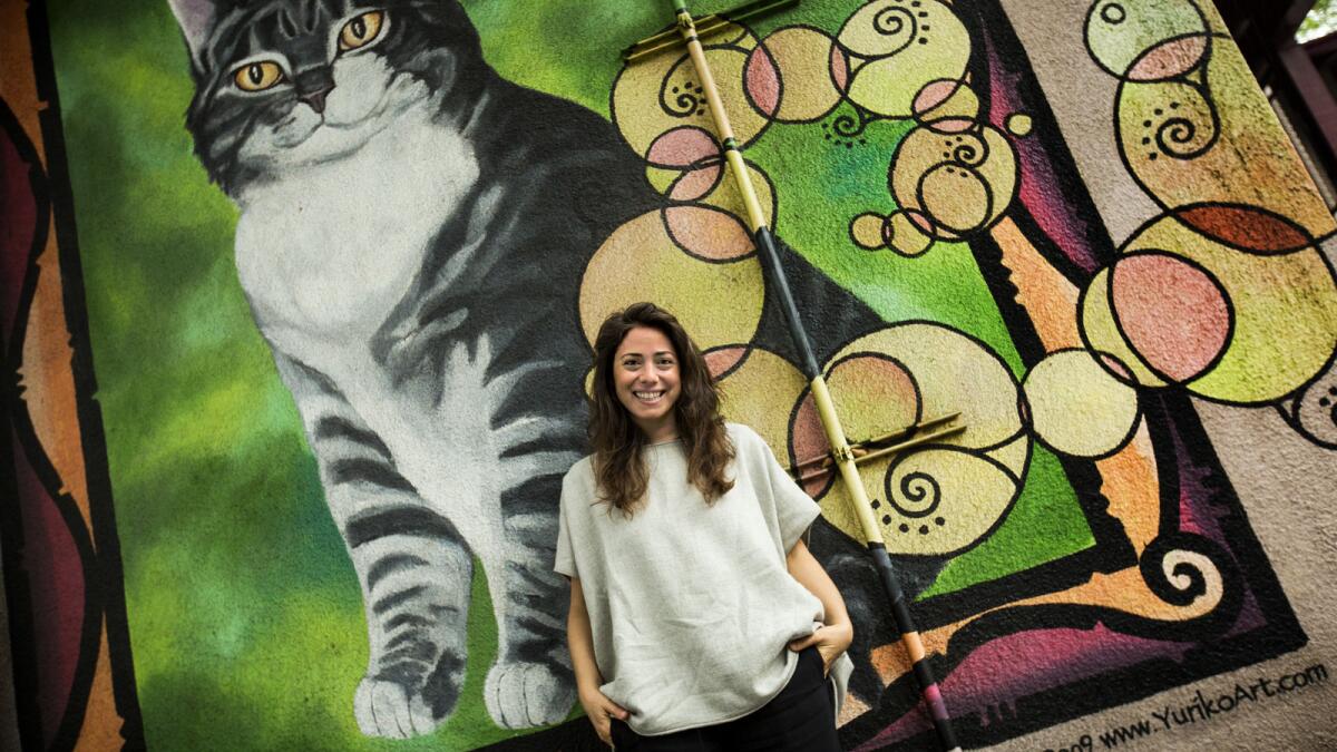 Director Ceyda Torun stands in front of a cat mural by Yuriko Art at Elysian Heights Elementary School in Los Angeles.