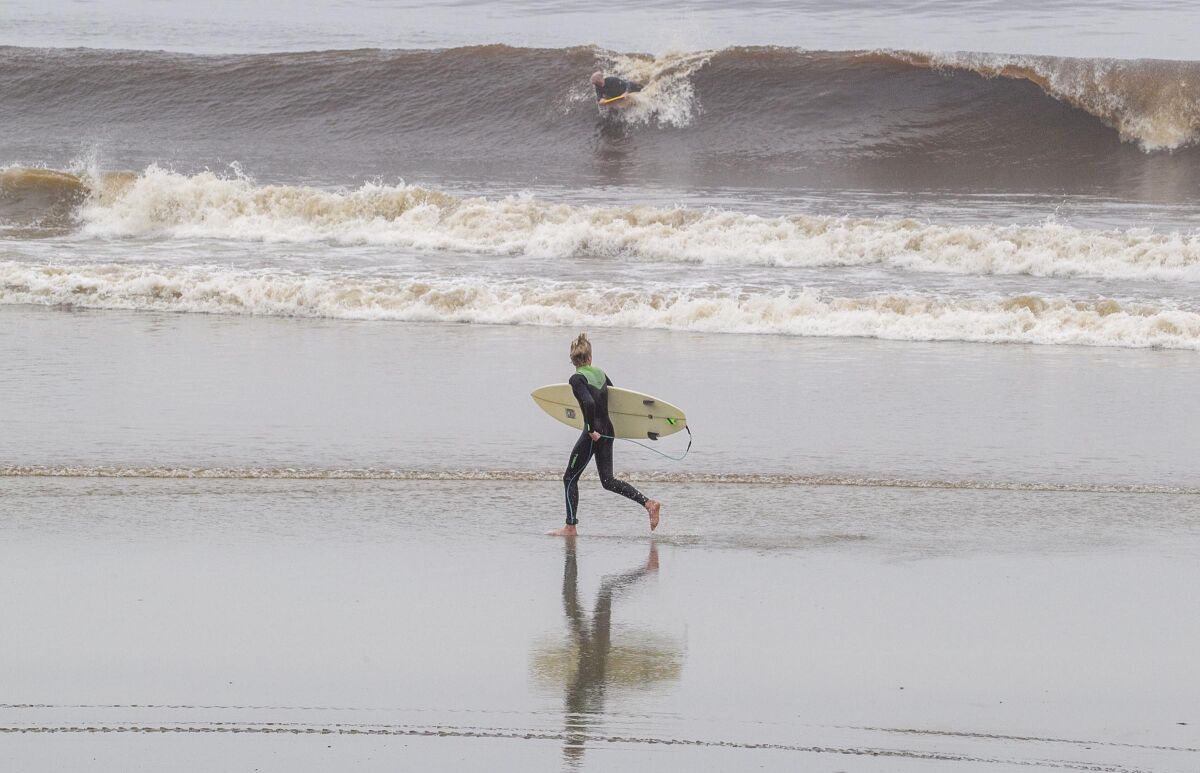 A surfer sprinting down Moonlight Beach in Encinitas 
