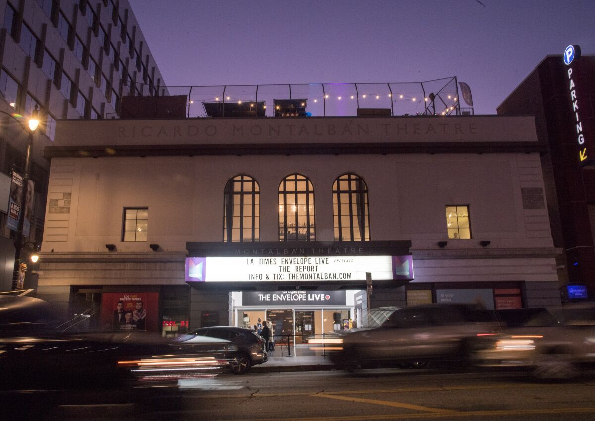The exterior façade of a movie theater at night with a brightly lit marquee.