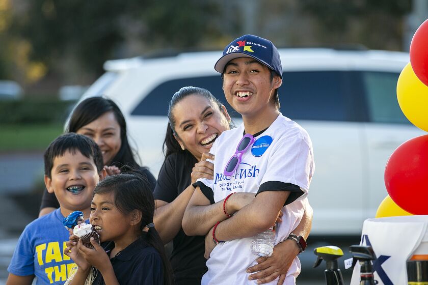 Costa Mesa, Ca - September 23: Moses Suarez, 20, and his mother Hortencia Zamora, along with Jake Zamora, left, and Kailyn Barragan, and Mirna Salgado, back left, watch as employees at Fix Auto Costa Mesa unveil his refurbished 2007 Ford Mustang on Friday, Sept. 23, 2022. Suarez who was diagnosed with leukemia in 2020 was granted his wish from Make-A-Wish Orange County and the Inland Empire for his car to be repaired. (Scott Smeltzer / Daily Pilot)
