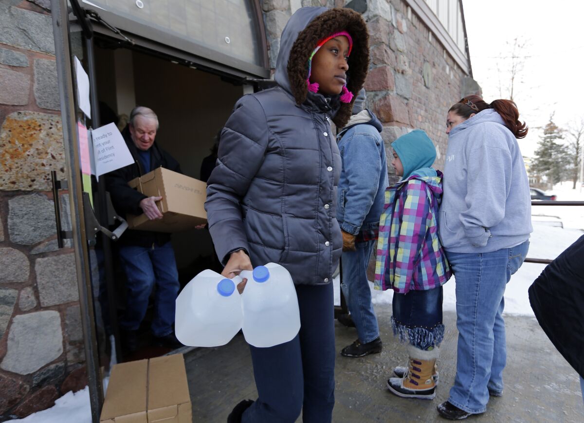 Genetha Campbell carries free water being distributed at the Lincoln Park United Methodist Church in Flint, Mich. Tom Gores led a campaign to raise funds amid the water crisis.