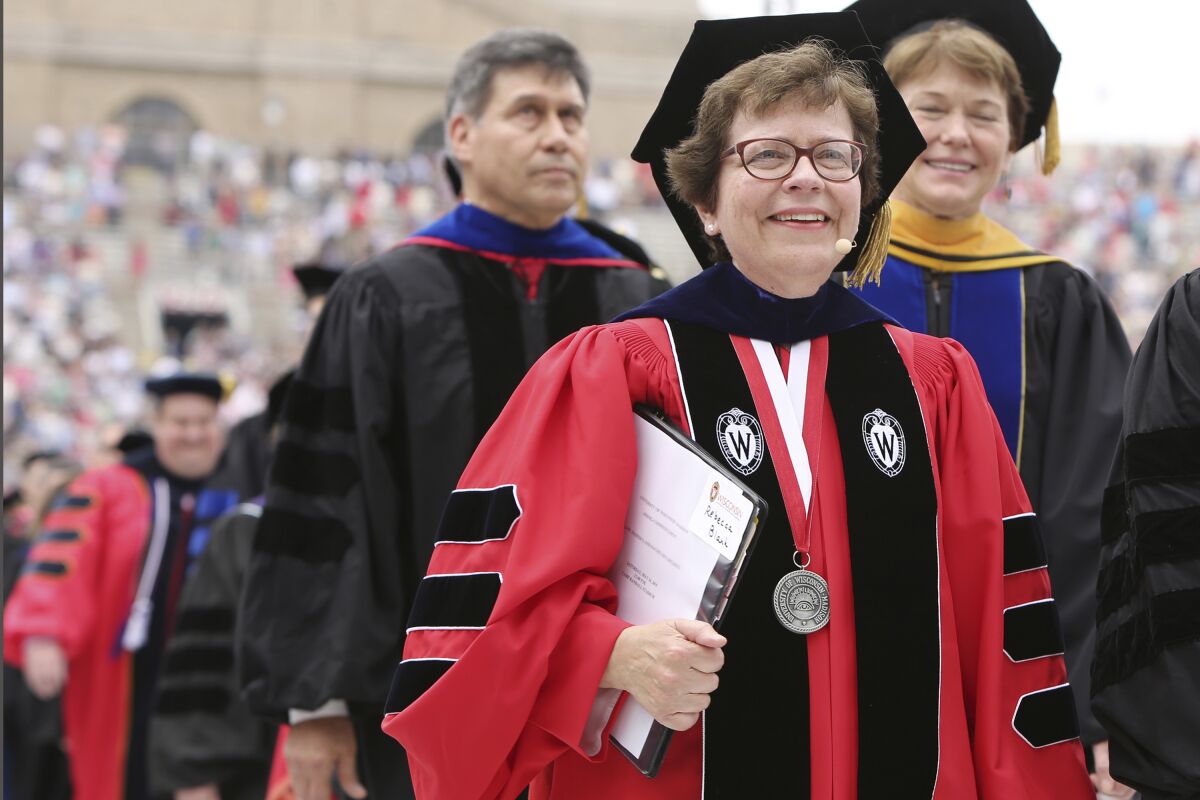 FILE - Then, Chancellor Rebecca Blank, center, walks in a procession at the start of the University of Wisconsin-Madison spring commencement ceremony in Madison, Wis., on May 16, 2015. Rebecca Blank, who was named last fall the first female president of Northwestern University, announced Monday, July 11, 2022, she is stepping down after being diagnosed with an aggressive form of cancer. (Amber Arnold/Wisconsin State Journal via AP, File)