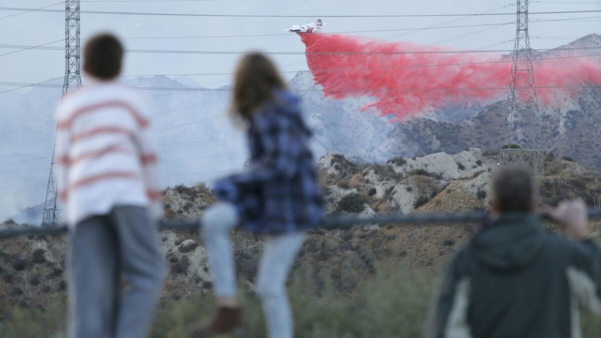 People watch a fire retardant drop from Poe Parkway in Stevenson Ranch.