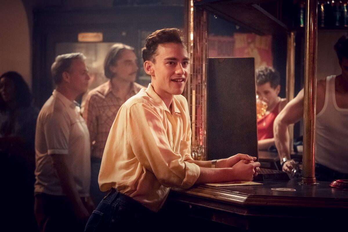 A young man leans on a bar in the miniseries "It's a Sin." 