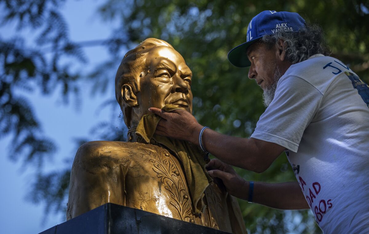 Alex Vanegas, a migrant from Nicaragua, cleans a bust of Nicaraguan poet Ruben Dario
