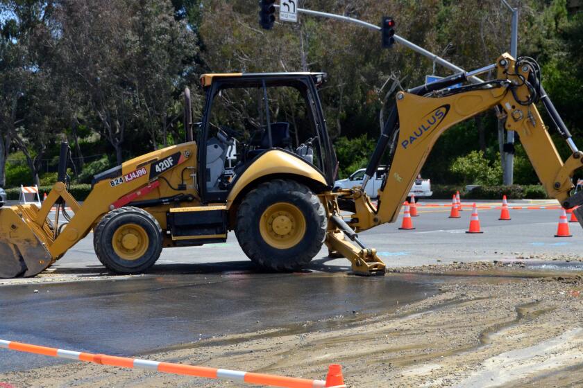 An excavator works on the opening where an Irvine Ranch Water District 20-inch water pipe broke.