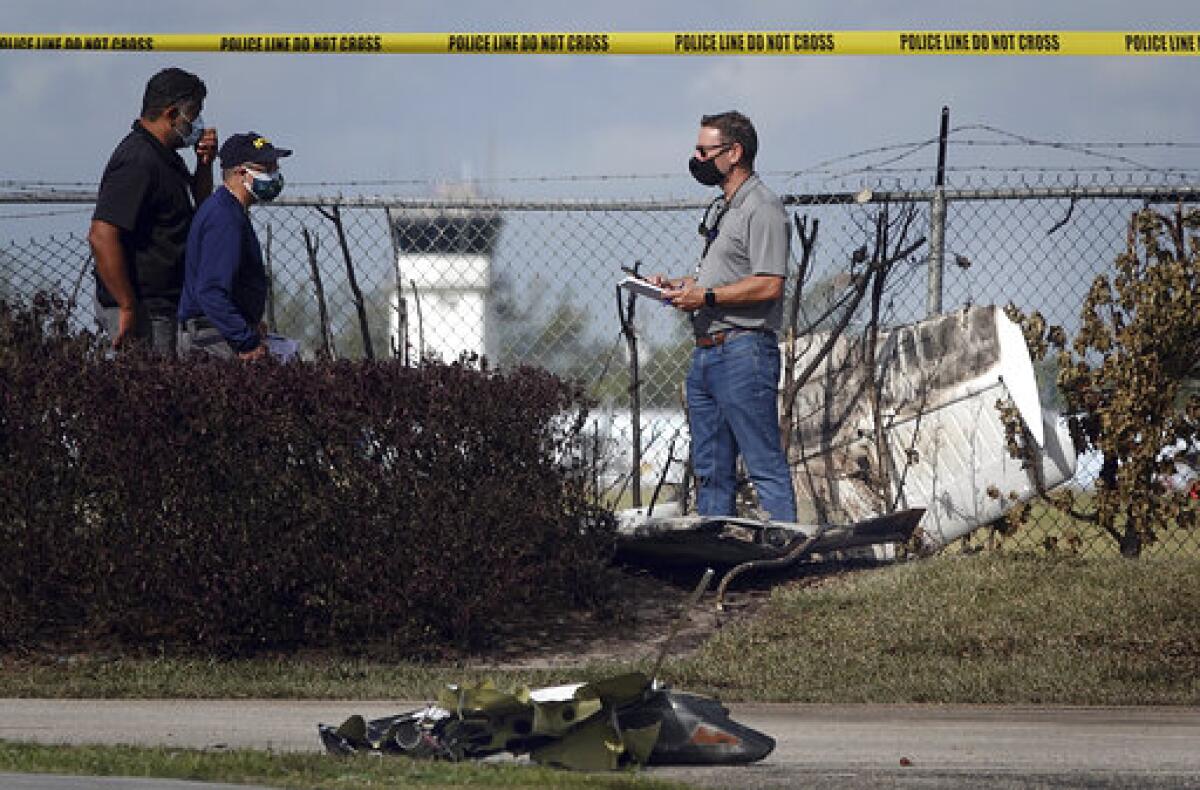 NTSB investigators work the scene of a plane crash near North Perry Airport in Pembroke Pines, Fla. Tuesday, March 16, 2021. A four-year-old child riding in a vehicle on the ground and the pilot and passenger in the plane were killed. (Joe Cavaretta/South Florida Sun-Sentinel via AP)