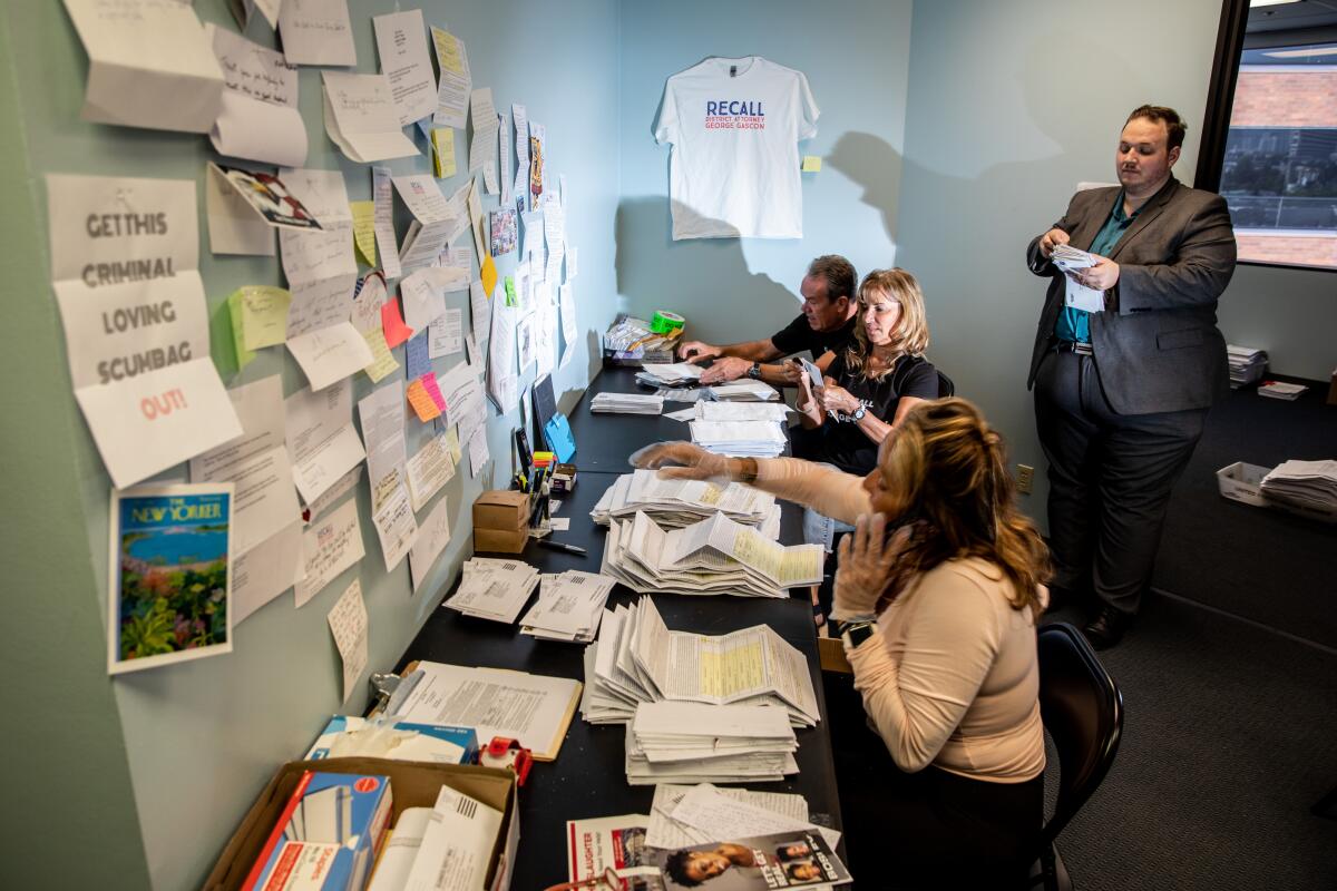 People sit at a table with stacks of paper in front of them 