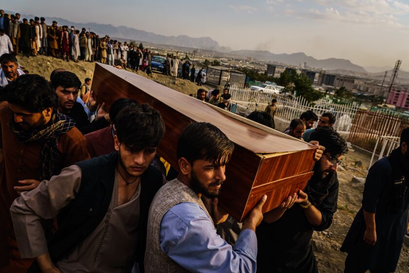 KABUL, AFGHANISTAN -- AUGUST 30, 2021: Caskets for the dead are carried towards the gravesite as relatives and friends attend a mass funeral for members of a family that is said to have been killed in a U.S. drone airstrike, in Kabul, Afghanistan, Monday, Aug. 30, 2021. (MARCUS YAM / LOS ANGELES TIMES)