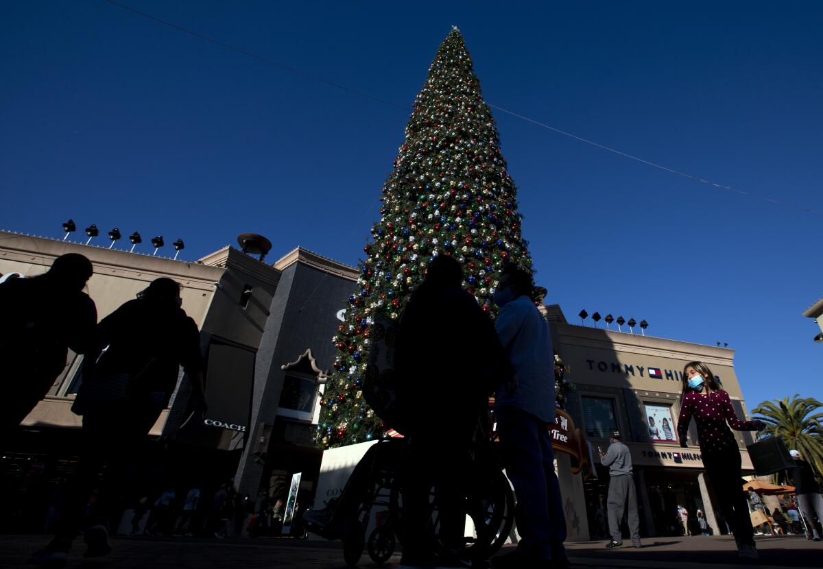 People walk around a large decorated Christmas tree at an outdoor mall