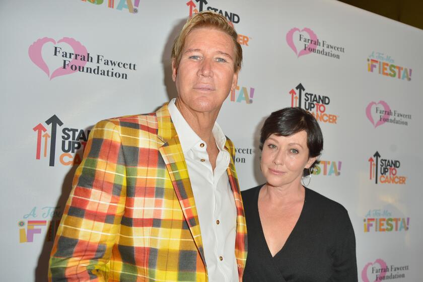Dr. Lawrence Piro wears a a bright plaid blazer while posing next to actor Shanen Doherty who is wearing a black v-neck