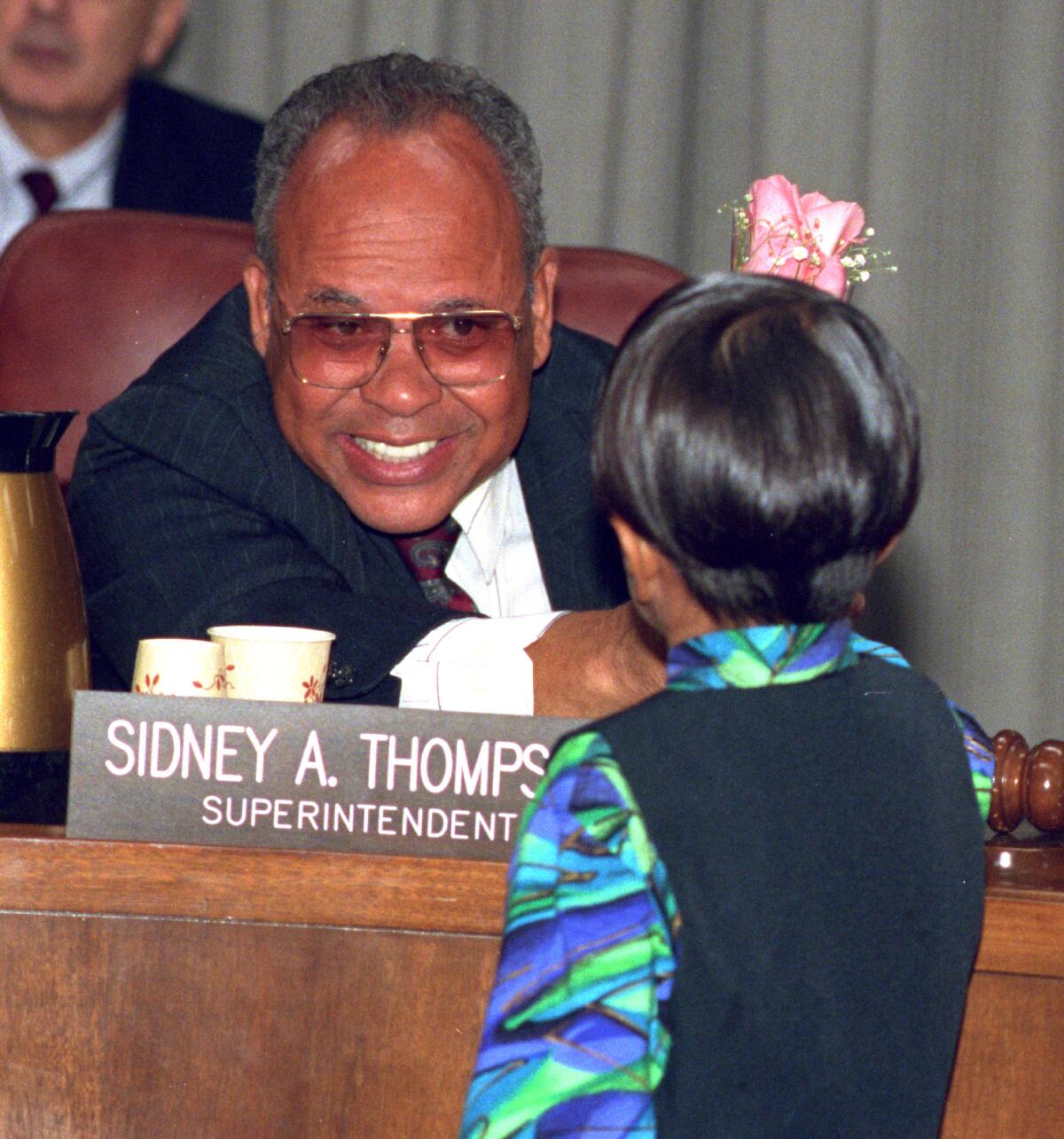 A seated man smiles at a child.