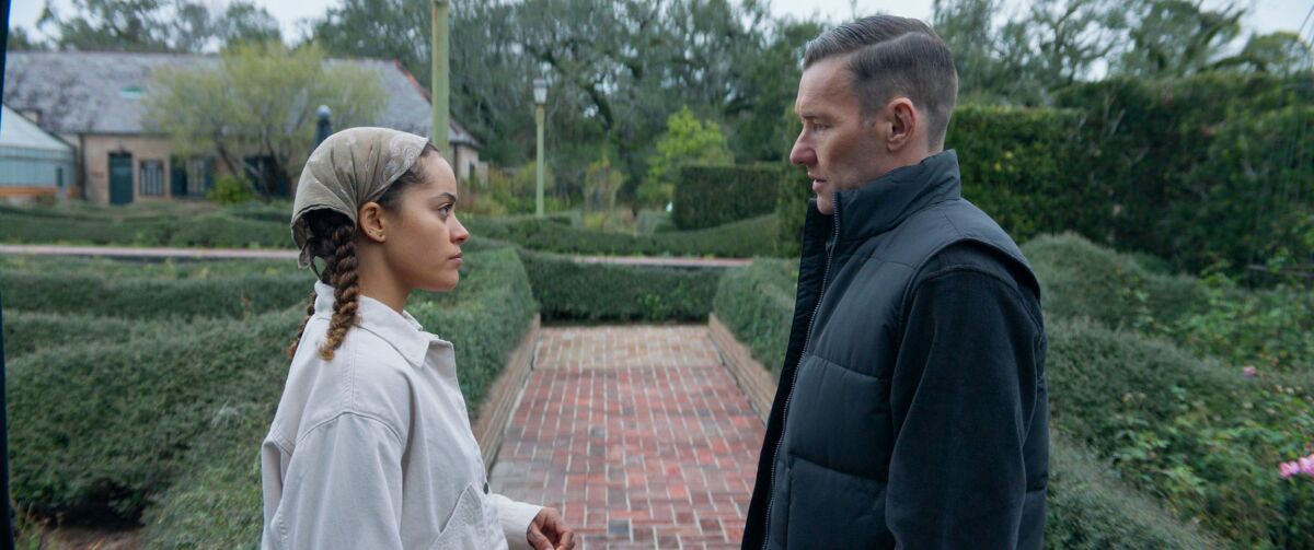 A young woman and a man stare at each other in a garden.