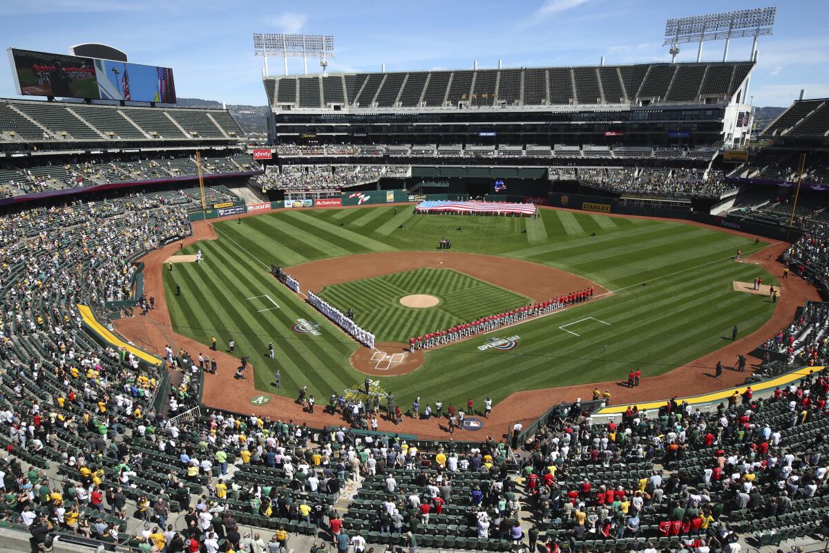 The Los Angeles Angels and Oakland Athletics stand for the national anthem at the Oakland Coliseum before a game in 2018.