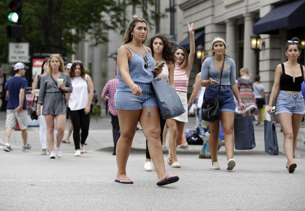 Consumers hold shopping bags as they walk along Michigan Avenue in Chicago on July 29.