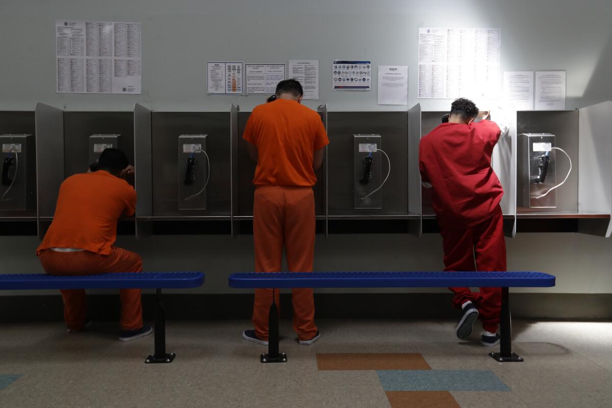 Three ICE detainees talk on telephones.