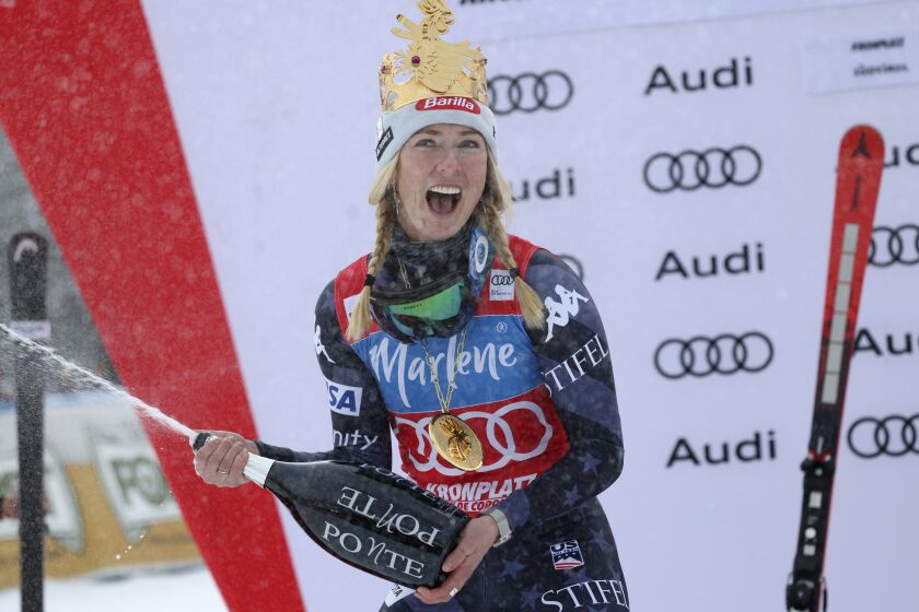 United States' Mikaela Shiffrin wears a crown and pops the cork as she celebrates on the podium