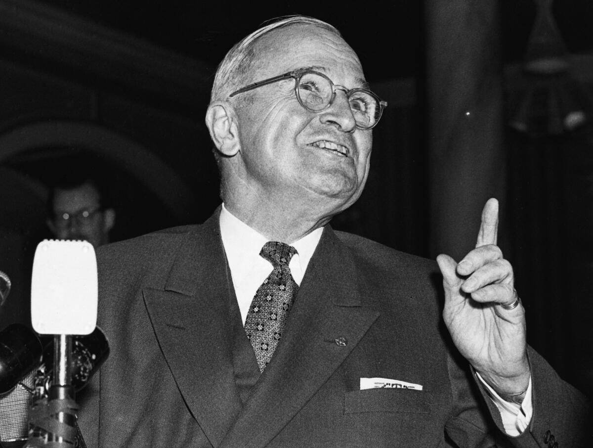 Former President Harry Truman speaks in London while holding up his hand.